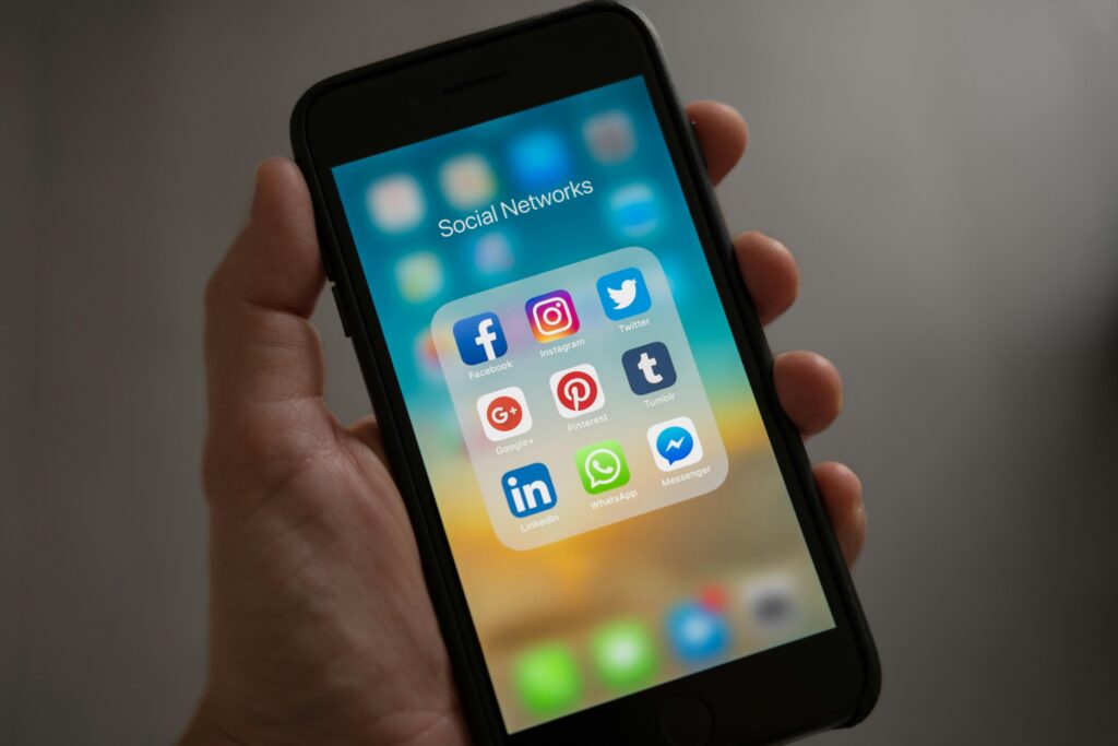 Smartphone screen showing various social media apps like Facebook, Instagram, Twitter, and WhatsApp, representing the Positive and Negative Impact of Internet on society.
